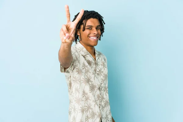Young african american rasta man joyful and carefree showing a peace symbol with fingers.