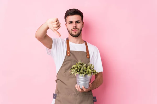 Joven Jardinero Caucásico Sosteniendo Una Planta Aislada Mostrando Gesto Aversión — Foto de Stock