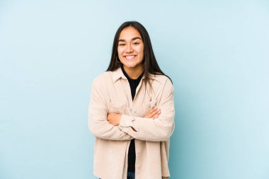 Mavi arka planda yalnız yaşayan genç bir kadın gülüyor ve eğleniyor..