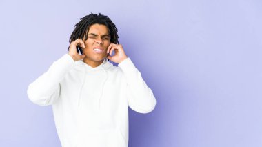 Genç Afrikalı Amerikalı Rasta adam kulaklarını parmaklarıyla kapatıyor, gürültülü bir ortam yüzünden stresli ve çaresiz..