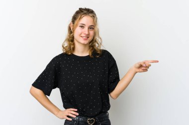 Beyaz arka planda genç beyaz kadın işaret parmağıyla işaret ederek gülümsüyor..