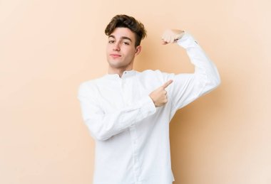 Beyaz tenli genç adam bej arka planda izole edilmiş. Güçlü bir hareket sergiliyor. Kadın gücünün sembolü.