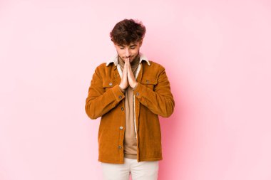 Pembe arka planda yalnız poz veren genç bir Arap.