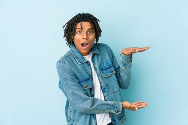 Kot ceket giyen genç siyahi adam ellerinin arasında bir fotokopi alanı tutarken şok oldu ve hayrete düştü..