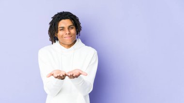 Genç Afrikalı Amerikalı Rasta adam elinde avuç içi bir şeyle kameraya teklif ediyor..