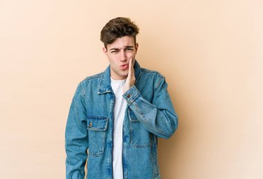 Beyazlı genç bir adam bej arka planda izole edilmiş güçlü bir diş ağrısı ve azı dişi ağrısı var..