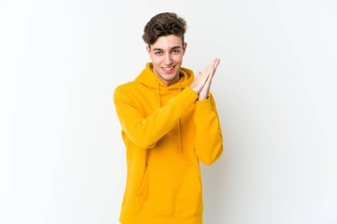 Beyaz arka planda izole olmuş genç beyaz bir adam enerjik ve rahat hissediyor, ellerini ovuşturuyor..