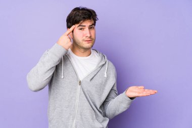 Mor arka planda izole edilmiş genç bir adam elinde bir ürün tutuyor..