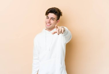Beyazların arka planında izole edilmiş genç beyaz adam parmaklarıyla ön tarafı işaret ediyor..