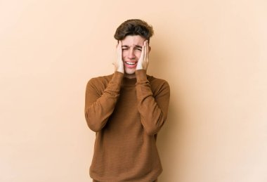 Beyaz tenli genç adam bej arka planda izole edilmiş sızlanıyor ve ağlıyordu..