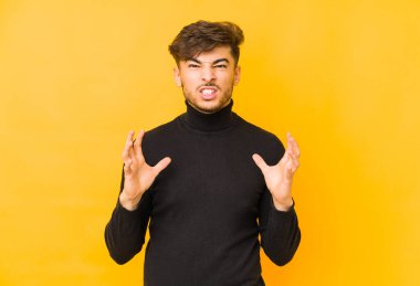 Sarı arka planda izole edilmiş genç Arap adam gergin elleriyle çığlık atıyor..