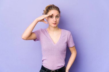 Mor arka plandaki genç beyaz kadın yüksek sesle bağırıyor, gözlerini açık ve ellerini gergin tutuyor..