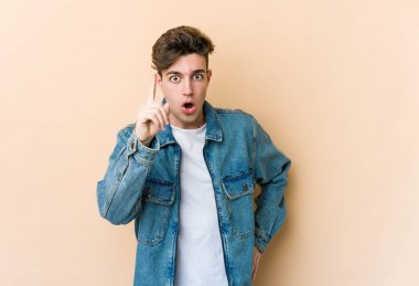 Beyazlı genç bir adam bej arka planda izole edilmiş. Bir fikri, ilham verici bir fikri var..