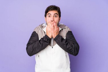 Mor arka planda izole edilmiş genç adam elleriyle ağzını kapatırken şok oldu..