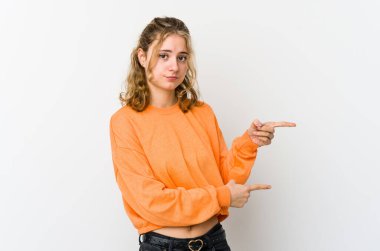 Beyaz arka plandaki genç beyaz kadın işaret parmağıyla fotokopi alanını işaret ederek şok oldu..