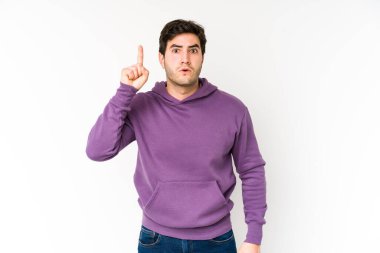 Beyaz arka planda izole edilmiş genç adam ağzı açık bir şekilde üst tarafı işaret ediyor..