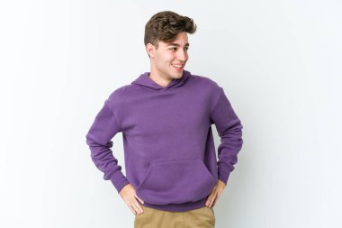 Beyaz arka planda izole genç beyaz adam mutlu bir şekilde gülüyor ve ellerini karnının üstünde tutarak eğleniyor..