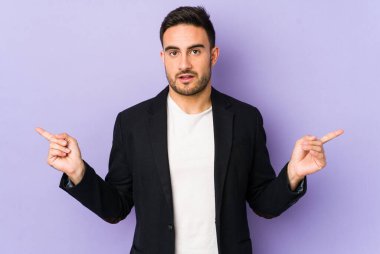 Mor arka planda izole edilmiş genç beyaz adam farklı kopya alanlarını gösteriyor, birini seçiyor, parmağıyla gösteriyor..