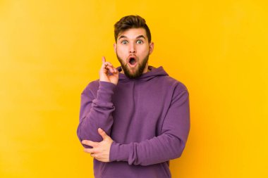 Sarı arka planda izole edilmiş genç beyaz bir adam harika bir fikri, yaratıcılık kavramı var..