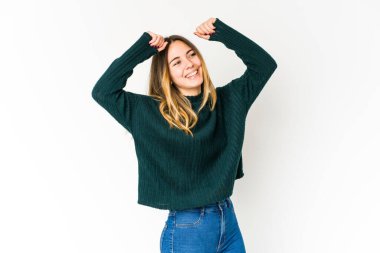 Beyaz arka planda izole edilmiş genç beyaz bir kadın özel bir günü kutluyor, atlıyor ve enerjiyle kollarını kaldırıyor..