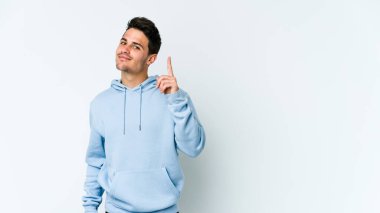 Beyaz arka planda izole edilmiş beyaz tenli genç bir adam bir numarayı parmağıyla gösteriyor..