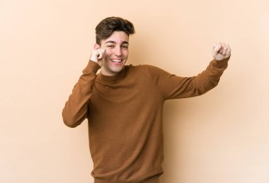 Genç beyaz adam bej arka planda izole edilmiş dans ediyor ve eğleniyor..