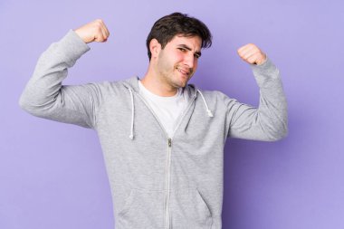 Mor arka planda izole edilmiş genç bir adam güçlü bir hareket gösteriyor, kollarıyla, kadınsı gücün sembolü.