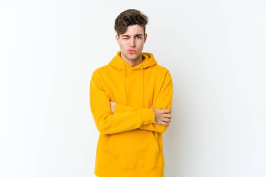 Beyaz arka planda izole edilmiş genç beyaz adam alaycı bir ifadeyle kameraya bakıyor..