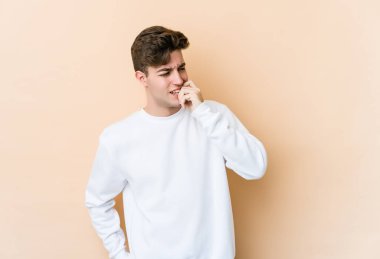 Beyaz tenli genç adam bej arka planda izole edilmiş. Rahatlamış bir şekilde fotokopi odasına bakan bir şey düşünüyor..