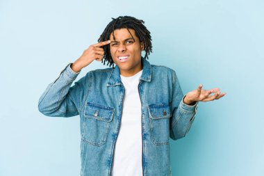 Kot ceket giyen genç siyah adam işaret parmağıyla hayal kırıklığı jesti yapıyor..