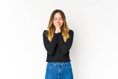 Beyaz arka planda izole edilmiş genç beyaz bir kadın el ele dua ederken, kendine güveniyor..