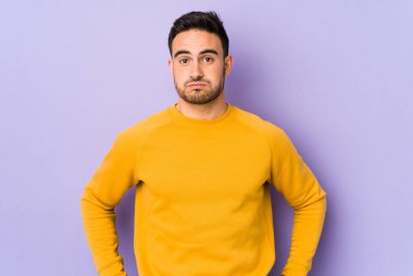 Mor arka planda izole edilmiş genç beyaz adamın yanakları şişer, yorgun bir ifadesi vardır. Yüz ifadesi kavramı.