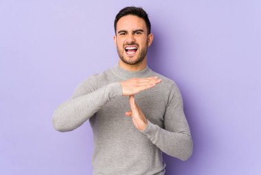 Mor arka planda izole edilmiş genç beyaz bir adam bir mola hareketi gösteriyor..