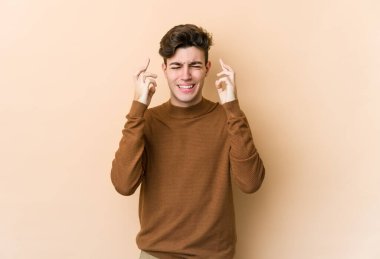 Beyazlı genç adam bej arka planda izole edilmiş şans dilemek için şans diliyor.