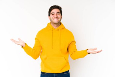 Beyaz arka planda soyutlanmış genç bir adam kollarıyla ölçek yapar, mutlu ve kendinden emin hisseder..