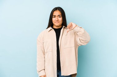 Mavi arka planda izole edilmiş genç bir kadın hoşlanmadığı bir jest gösteriyor. Anlaşmazlık konsepti.