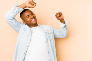 Genç latin adam bej arka planda izole kollarını uzatarak, rahat bir konumda..