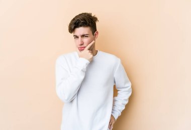 Beyazlı genç bir adam bej arka planda izole edilmiş. Bir strateji planlıyor, bir iş yolu düşünüyor..