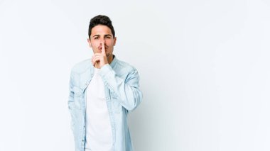 Beyaz arka planda izole edilmiş genç beyaz bir adam ya sır saklıyor ya da sessizlik istiyor..