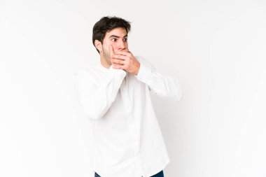 Genç adam beyaz arka planda izole edilmiş. Düşünceli bir şekilde bir fotokopi odasına bakıyor. Ağzını eliyle kapatıyor..