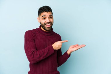 Genç, melez, Arap bir adam. Palmiye üzerinde bir kopya alanı tutarken heyecanlı..