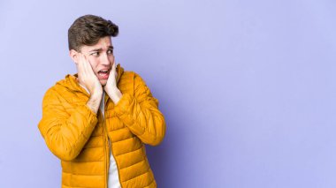 Mor arka planda izole edilmiş genç beyaz adam korkmuş ve korkmuş..