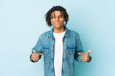 Kot ceketli genç bir adam gömlek fotokopi odasını elle işaret ediyor, gururlu ve kendinden emin.