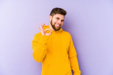 Mor arka planda izole edilmiş genç adam neşeli ve kendinden emin, iyi bir hareket gösteriyor..