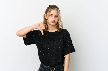 Beyaz arka plandaki genç beyaz kadın hoşlanmadığı bir hareket sergiliyor, başparmakları aşağıda. Anlaşmazlık konsepti.