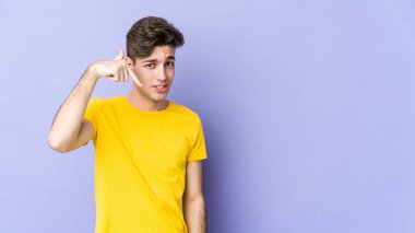 Mor arka planda izole olmuş genç beyaz bir adam gömlek fotokopisini elle gösteriyor, gururlu ve kendinden emin.