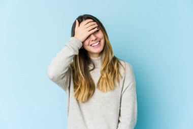 Mavi arka planda soyutlanmış beyaz bir kadın elleriyle gözlerini kapatıyor, gülümseyerek bir sürpriz bekliyor..