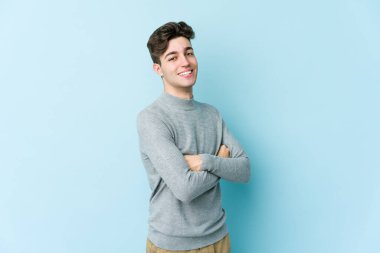 Mavi arka planda izole edilmiş genç beyaz adam mutlu, güler yüzlü ve neşeli.