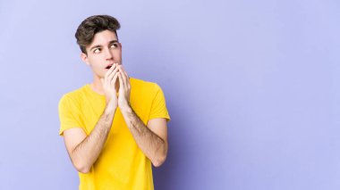 Kafkasyalı genç bir adam mor arka planda izole edilmiş bir plan yapıyor, bir fikir kuruyor..