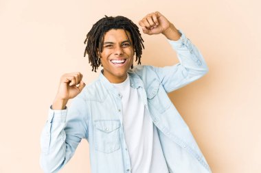 Genç Afrikalı Amerikalı Rasta adam özel bir günü kutluyor, atlıyor ve enerjiyle kollarını kaldırıyor..